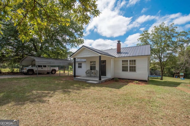 view of front of home featuring a trampoline, a front yard, and a carport