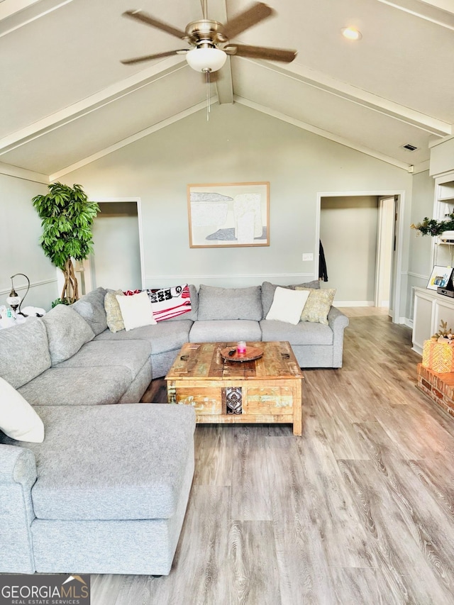 living room with ceiling fan, hardwood / wood-style floors, and vaulted ceiling with beams