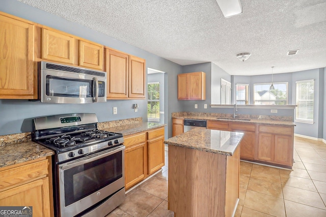 kitchen featuring sink, light tile patterned floors, decorative light fixtures, a kitchen island, and stainless steel appliances