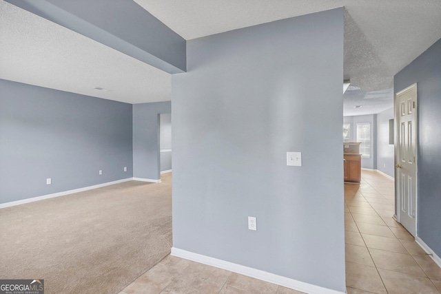 hallway with light carpet and a textured ceiling