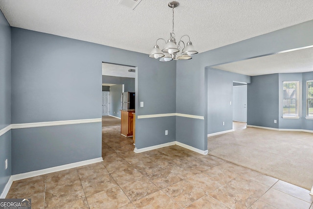 empty room featuring light carpet, a textured ceiling, and a notable chandelier