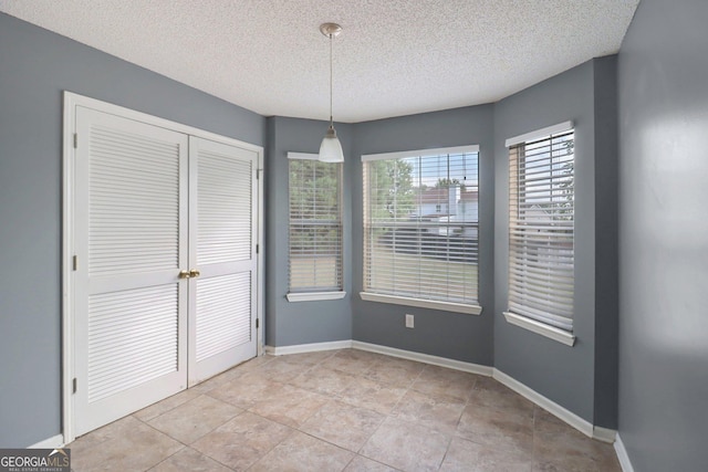 unfurnished dining area featuring light tile patterned floors and a textured ceiling