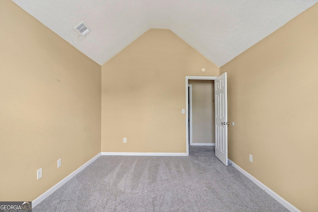 carpeted empty room with a textured ceiling and vaulted ceiling