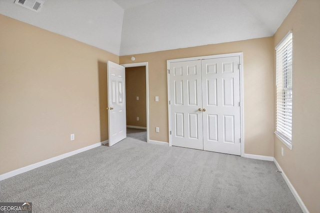 unfurnished bedroom with light colored carpet, vaulted ceiling, and a closet