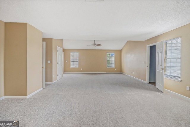 empty room featuring a textured ceiling, ceiling fan, light carpet, and vaulted ceiling