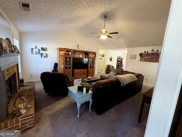 living room featuring vaulted ceiling, a brick fireplace, a textured ceiling, dark carpet, and ceiling fan