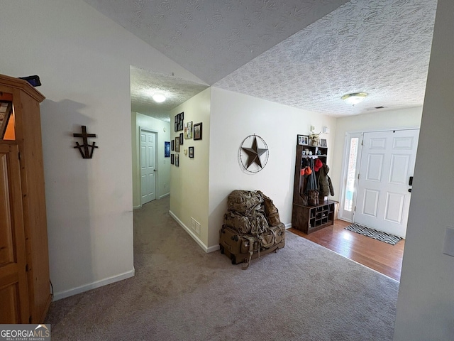 entrance foyer with vaulted ceiling, carpet, and a textured ceiling