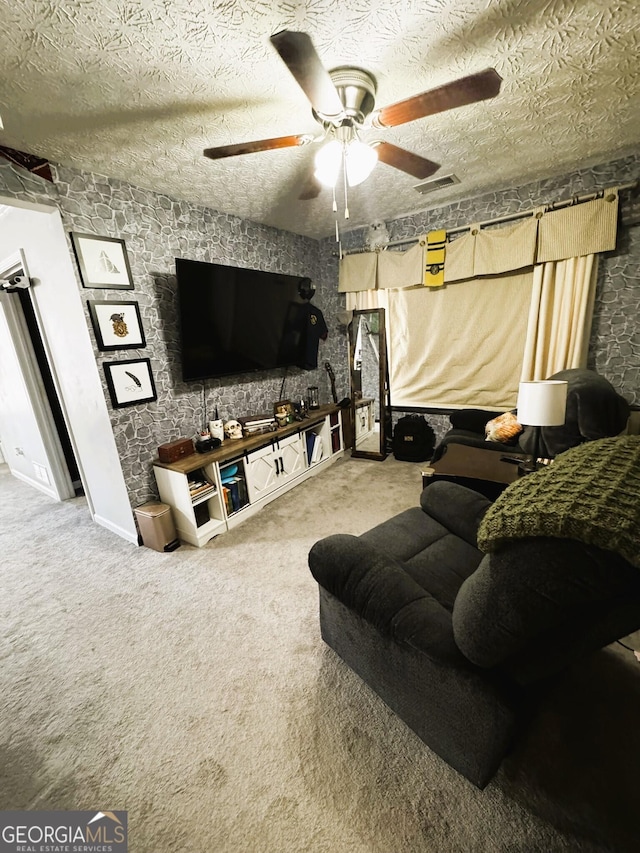 living room featuring ceiling fan, carpet floors, and a textured ceiling