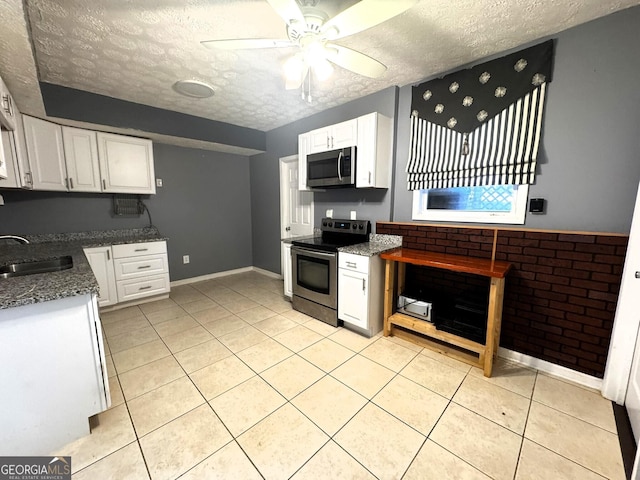 kitchen with sink, appliances with stainless steel finishes, white cabinetry, a textured ceiling, and light tile patterned flooring