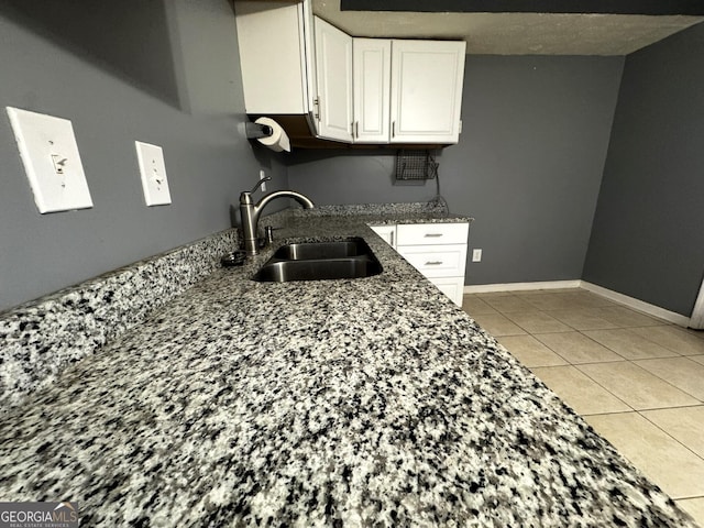 504 Plantation Creek Dr, Loganville, GA 30052 - kitchen with baseboards, dark stone countertops, light tile patterned floors, white cabinetry, and a sink