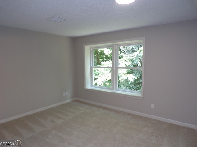 carpeted empty room featuring a textured ceiling