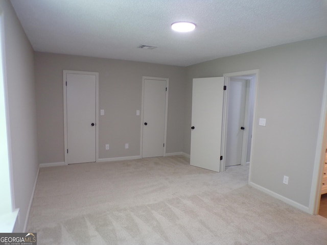 interior space with a textured ceiling and light carpet