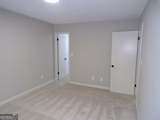 empty room with a textured ceiling and light carpet