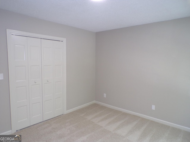 unfurnished bedroom with light colored carpet and a closet