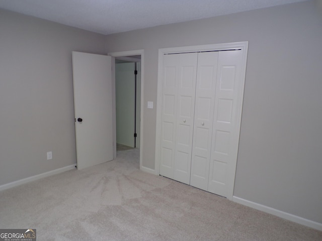 unfurnished bedroom featuring light carpet and a closet