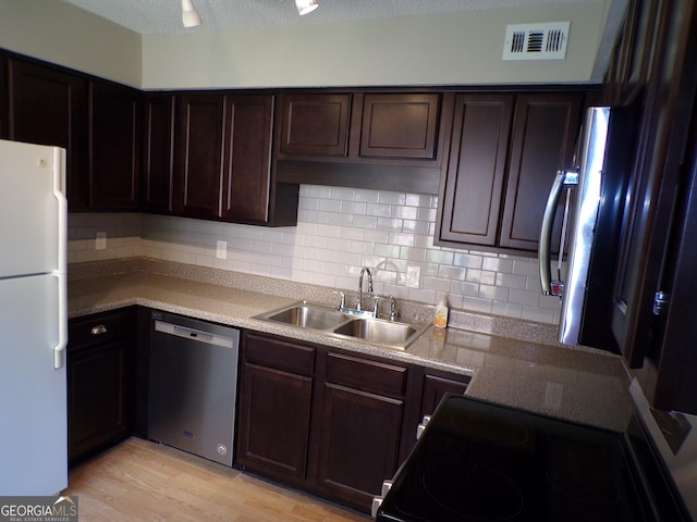 kitchen featuring tasteful backsplash, dark brown cabinets, stainless steel appliances, sink, and light hardwood / wood-style flooring