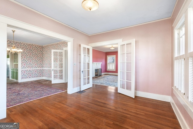 spare room with french doors, dark hardwood / wood-style flooring, crown molding, and a chandelier