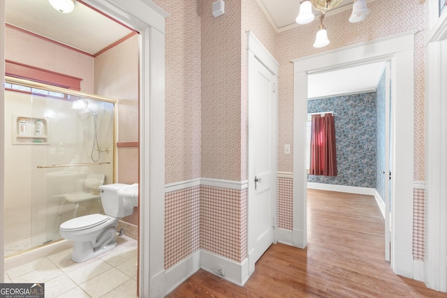 bathroom with toilet, crown molding, a shower with shower door, and hardwood / wood-style floors