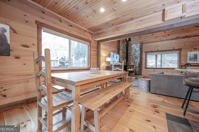 dining space featuring light hardwood / wood-style flooring, a wood stove, and wooden walls