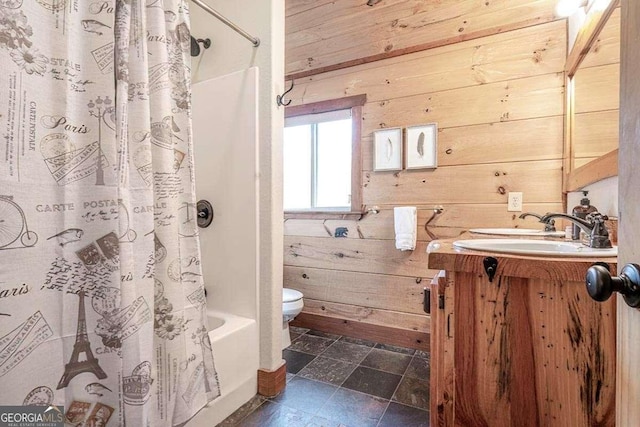 full bathroom with wood walls, shower / bath combo with shower curtain, vanity, and toilet