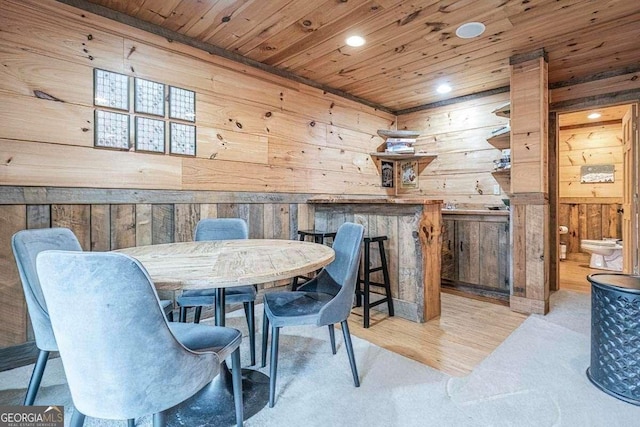 carpeted dining space with wooden walls and wood ceiling