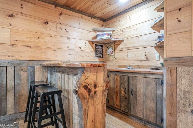 bar with light wood-type flooring, wooden ceiling, and wooden walls