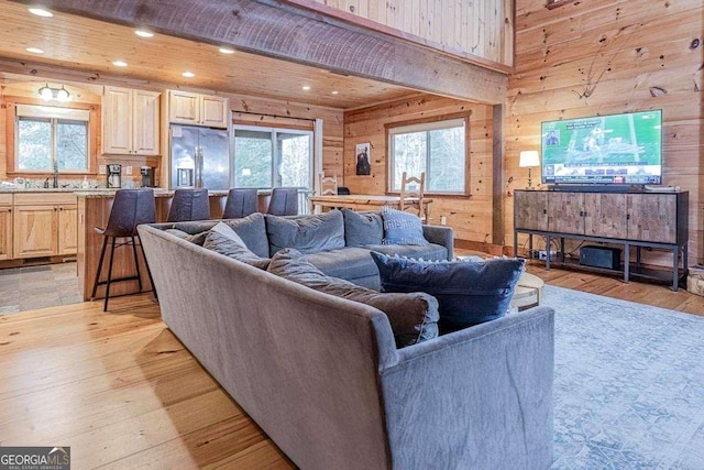 living room featuring sink, light hardwood / wood-style floors, wooden ceiling, and wood walls