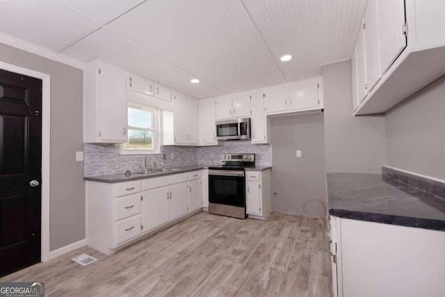 kitchen featuring white cabinetry, sink, backsplash, light hardwood / wood-style floors, and appliances with stainless steel finishes