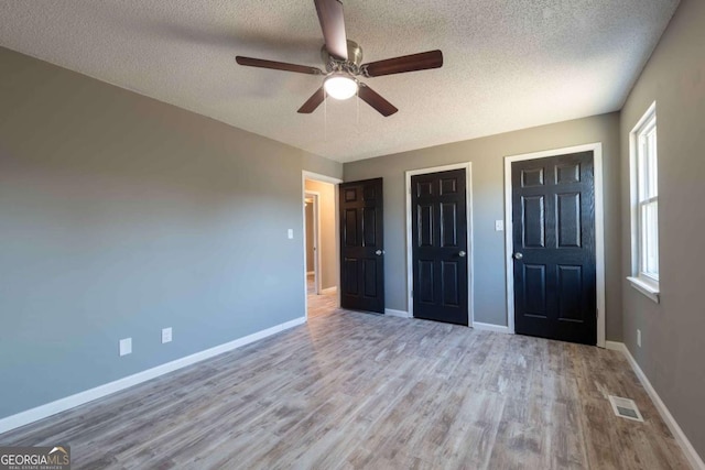 unfurnished bedroom featuring ceiling fan, light wood-type flooring, and a textured ceiling