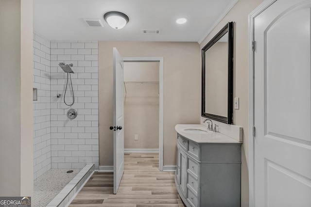 bathroom featuring a tile shower, vanity, and hardwood / wood-style flooring