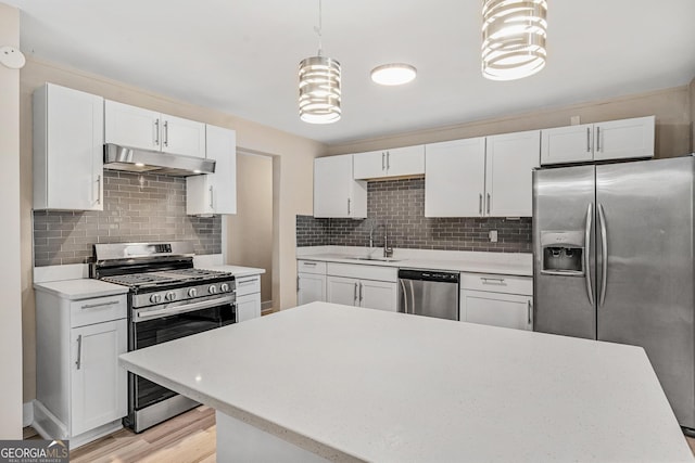 kitchen with sink, tasteful backsplash, decorative light fixtures, white cabinets, and appliances with stainless steel finishes