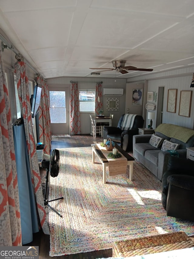 living room with a wall unit AC and ceiling fan