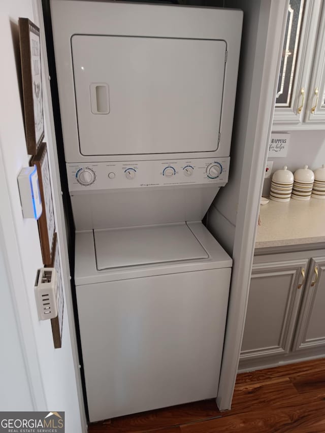 washroom with dark hardwood / wood-style flooring and stacked washer and dryer