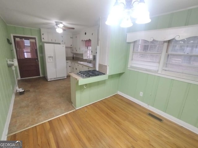 kitchen featuring sink, stainless steel gas cooktop, white refrigerator with ice dispenser, white cabinets, and light wood-type flooring