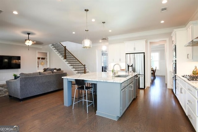 kitchen featuring sink, white cabinetry, a kitchen island with sink, and hanging light fixtures