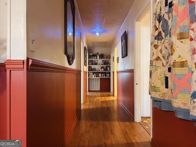 hallway with wood-type flooring, crown molding, and wood walls