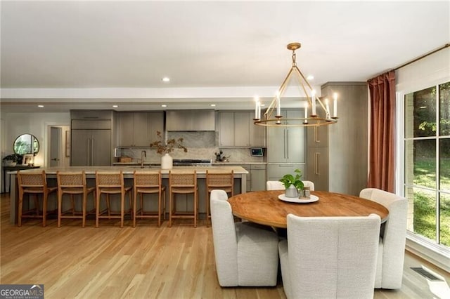 dining area featuring light hardwood / wood-style flooring, a chandelier, and sink