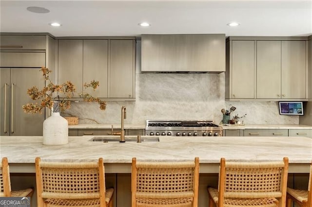 kitchen featuring gray cabinetry, a breakfast bar, wall chimney range hood, sink, and decorative backsplash