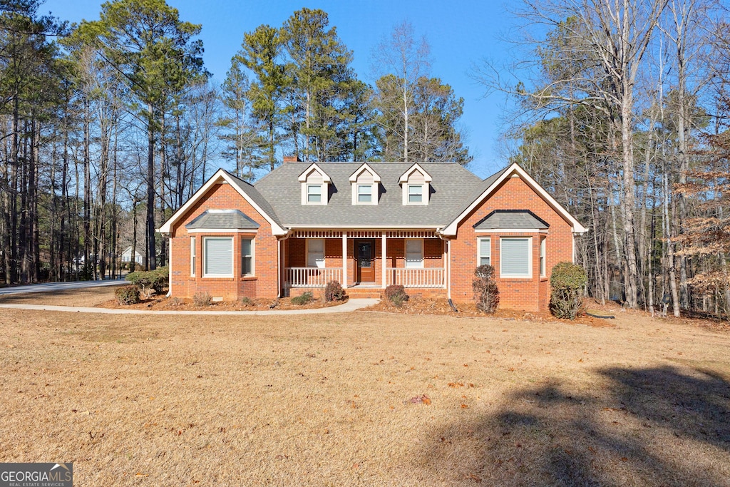 cape cod home featuring covered porch and a front yard