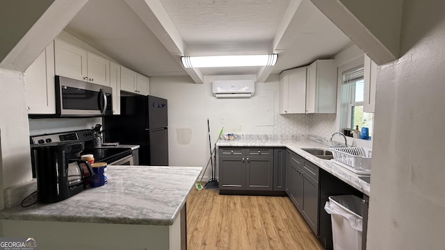 kitchen with gray cabinetry, stainless steel appliances, a wall mounted air conditioner, backsplash, and white cabinets