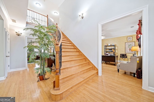 staircase with crown molding, visible vents, wood finished floors, and baseboards