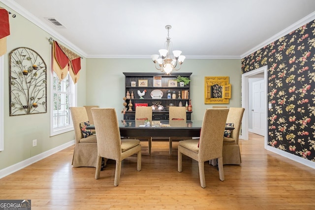 dining room featuring crown molding, an inviting chandelier, light wood finished floors, and visible vents