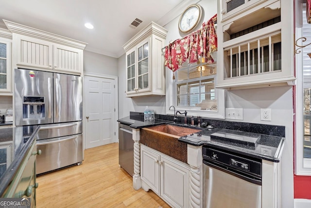 kitchen featuring ornamental molding, visible vents, light wood-style floors, stainless steel appliances, and glass insert cabinets