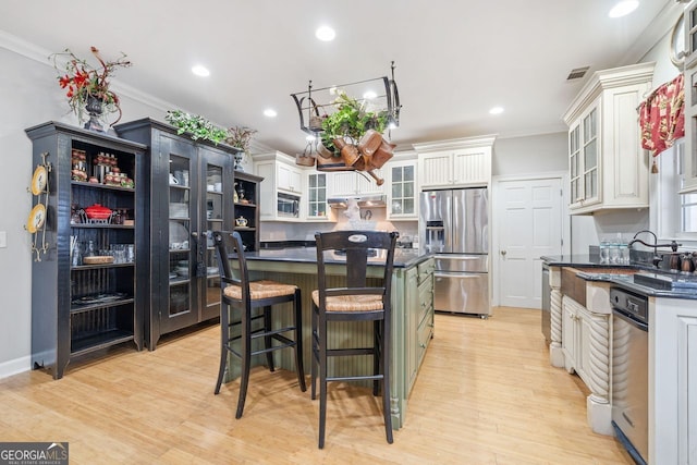 kitchen featuring dark countertops, a center island, stainless steel appliances, white cabinetry, and glass insert cabinets