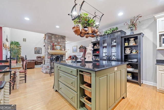 kitchen with crown molding, green cabinetry, visible vents, open shelves, and a kitchen island