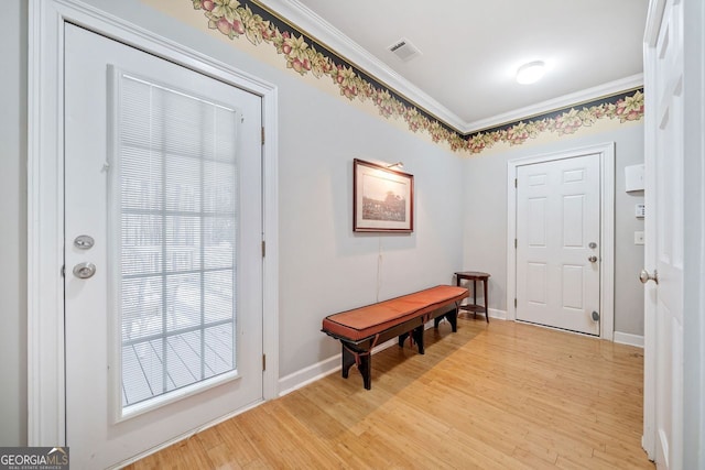 doorway featuring crown molding, visible vents, baseboards, and light wood-type flooring