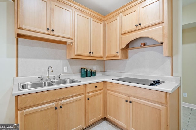 kitchen with a sink, light countertops, black electric stovetop, and light brown cabinets