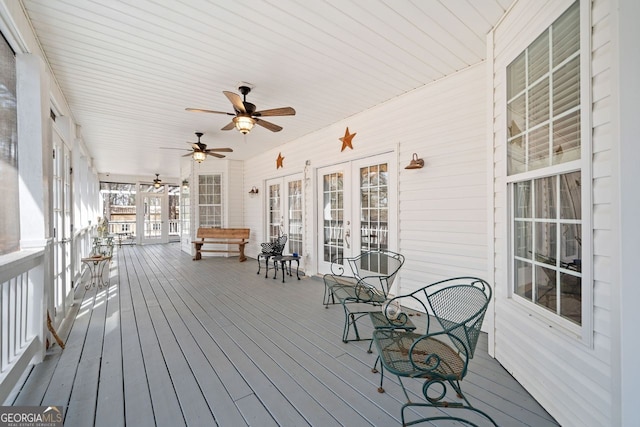 wooden terrace featuring covered porch, a ceiling fan, and french doors