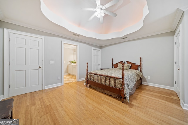 bedroom featuring baseboards, visible vents, a tray ceiling, and wood finished floors