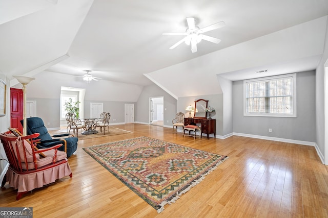 living area featuring baseboards, visible vents, a ceiling fan, lofted ceiling, and wood finished floors